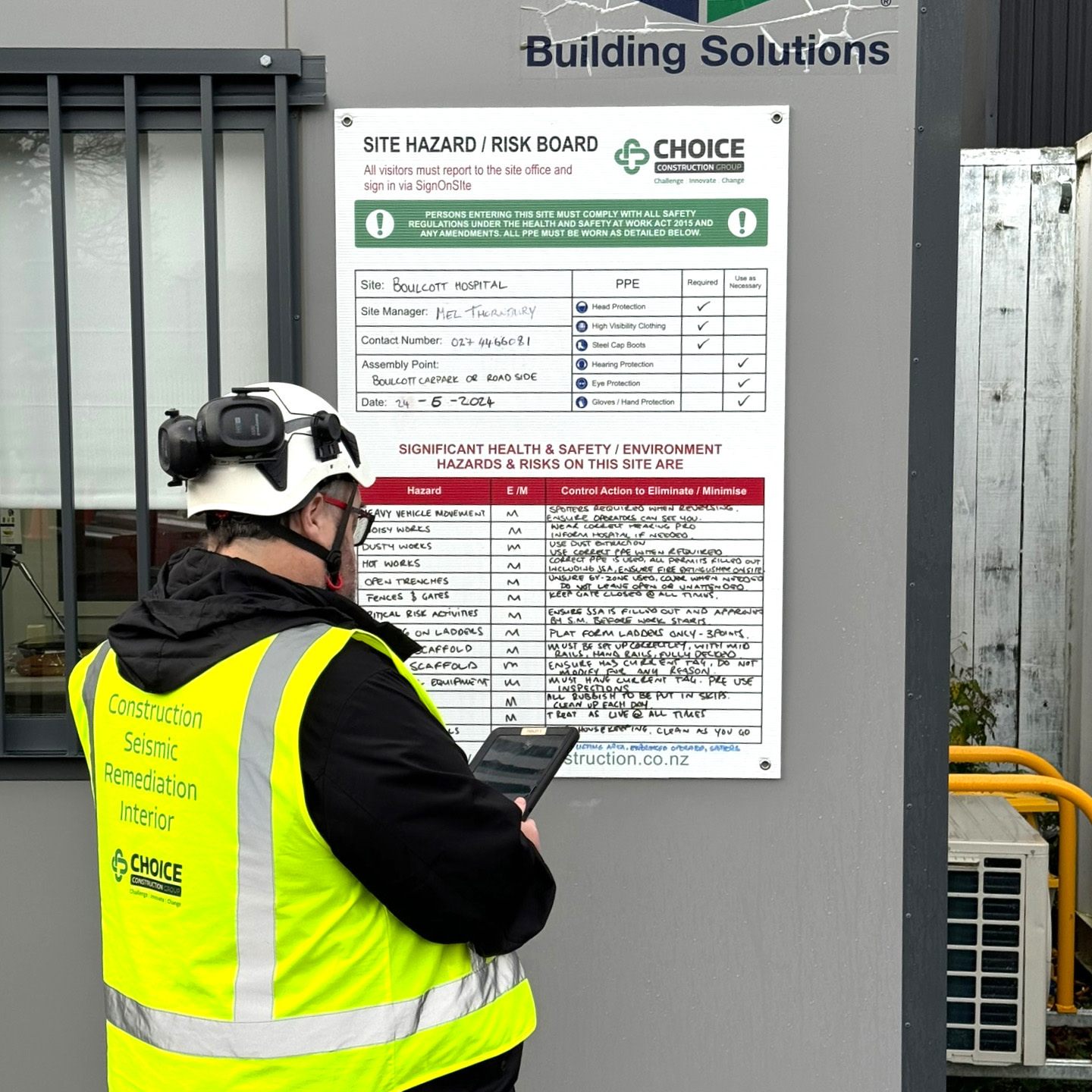 A man in a safety vest using a tablet.